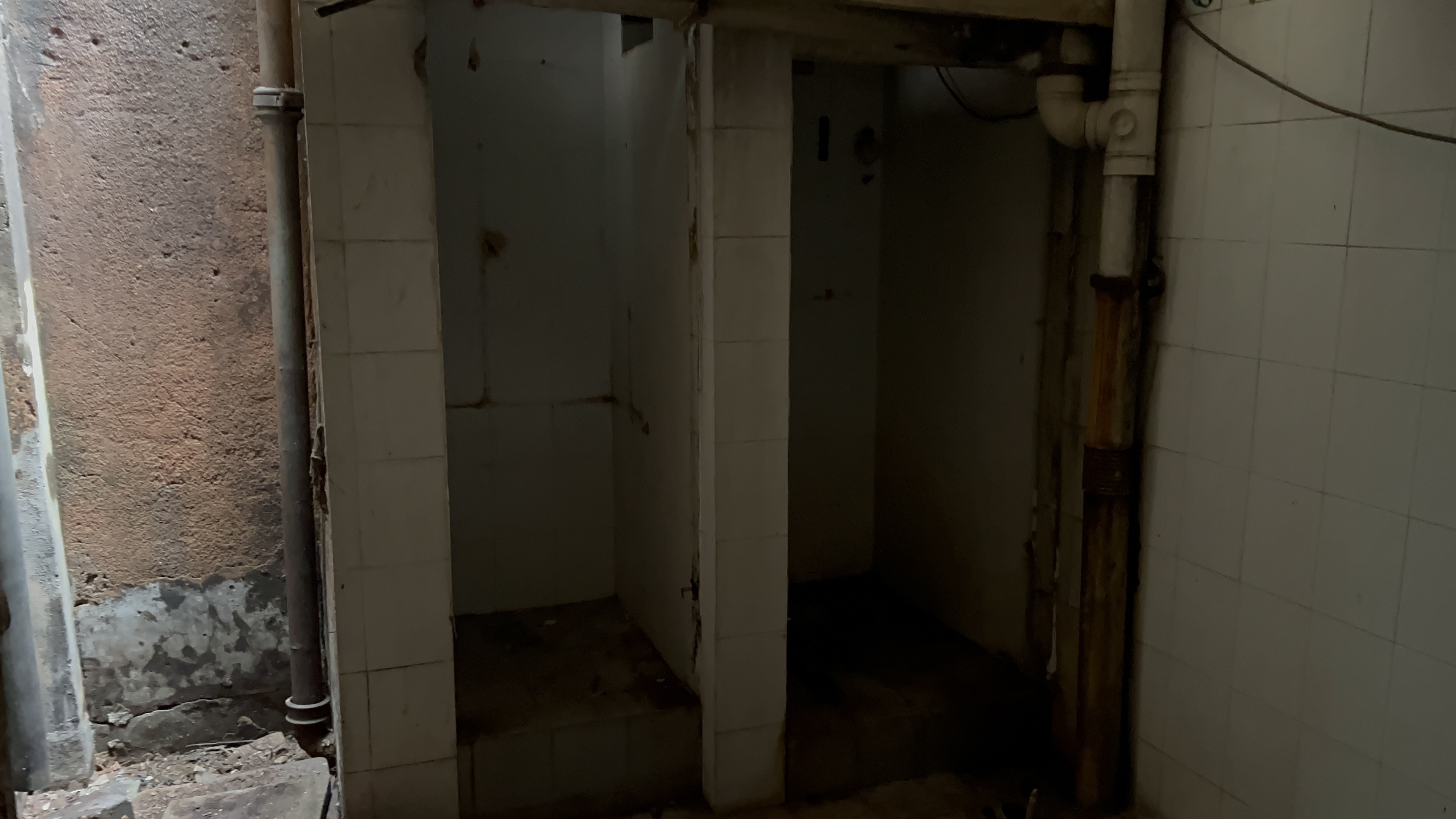 Old tiled toilet stalls, damp and barely usable.