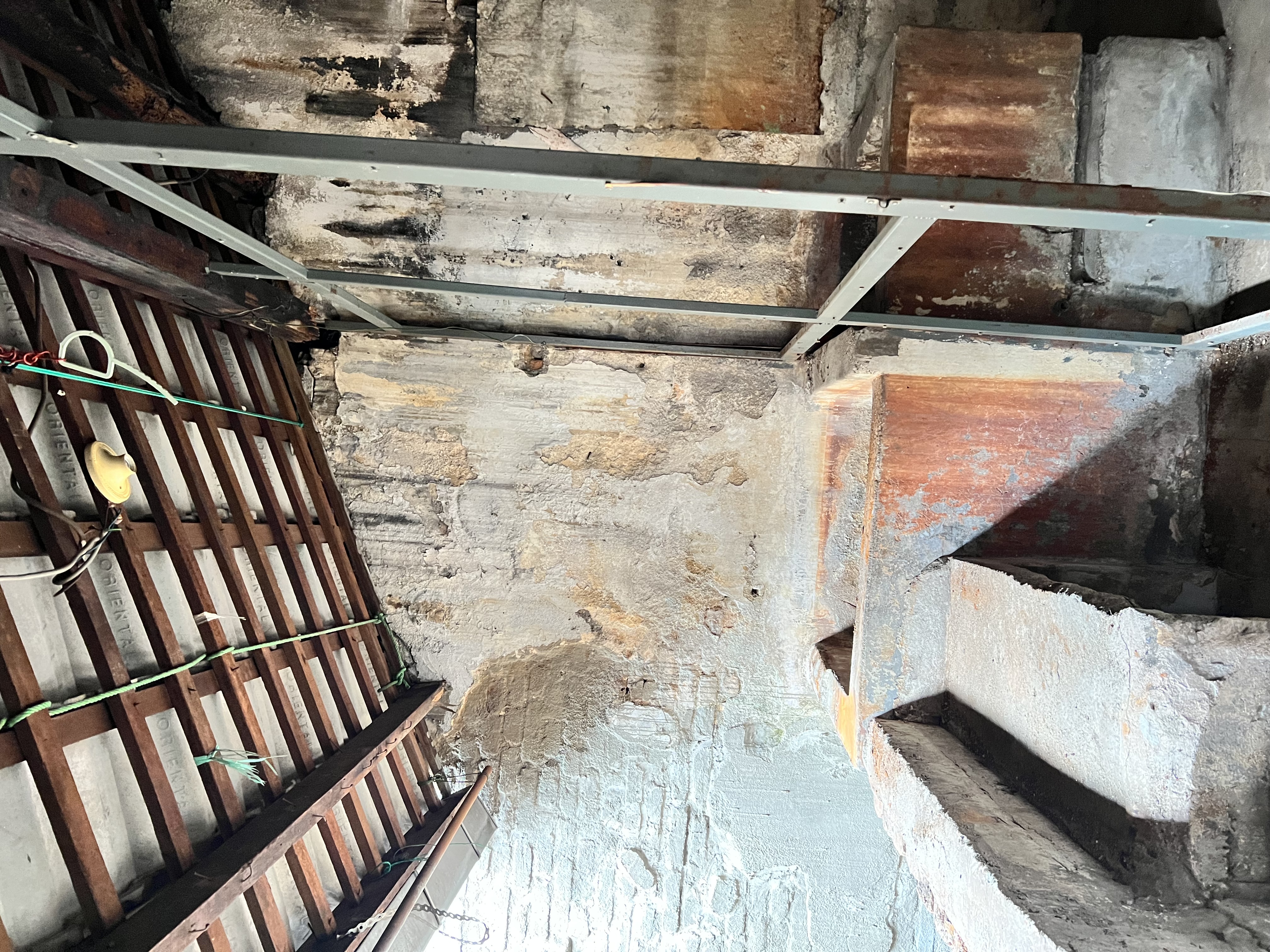 First-floor mezzanine with exposed railing and patchwork repairs.